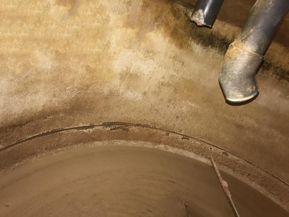 Close-up view of an empty liquid feed mixing tank with visible signs of wear and tear.