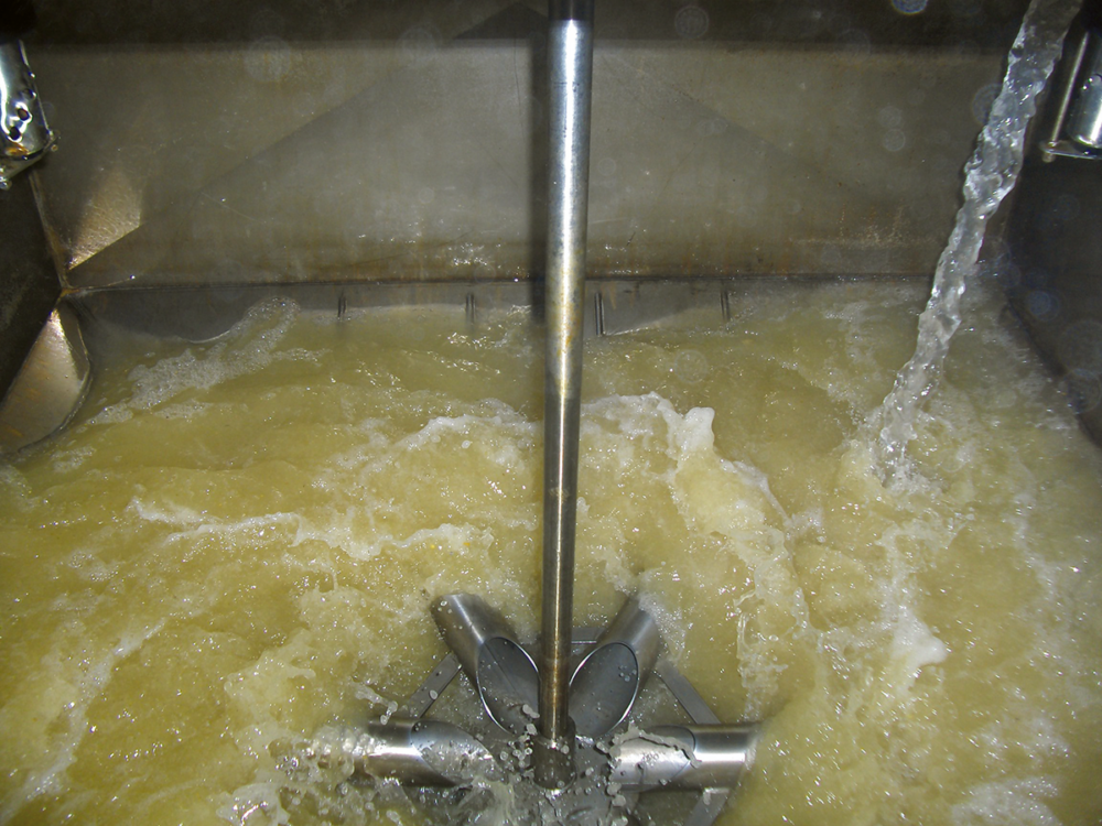 Close-up view of a liquid feed mixing tank during the process of washing.